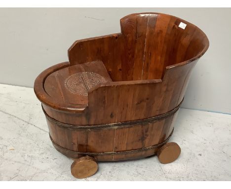 A hard wood child's chair/bath tub, with raised back and removable tray, on wheels, 62cm long 