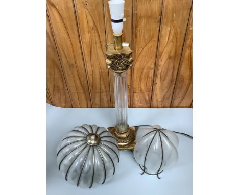 A tall gilt lamp stand shaped as a classical column with clear central glass pillar, raised on square base to four decorative