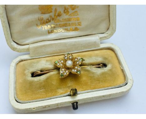 A 15ct gold pearl and peridot set bar-brooch, modelled as a flower weighing 2.5 grams, in fitted Searle &amp; Co box. 