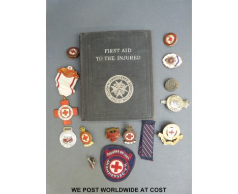A collection of British Red Cross Society badges and medals and a First Aid book