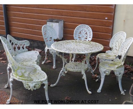 An ornate cast metal set of garden furniture including a bench raised on six legs, table and four chairs 