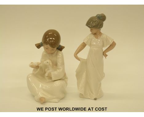 Two Nao figures, one a girl holding a lamb, the other a girl with white dress