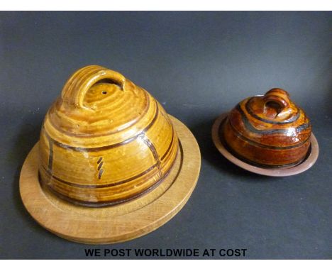 A Winchcombe Pottery style cheese dome with oak board and another smaller example