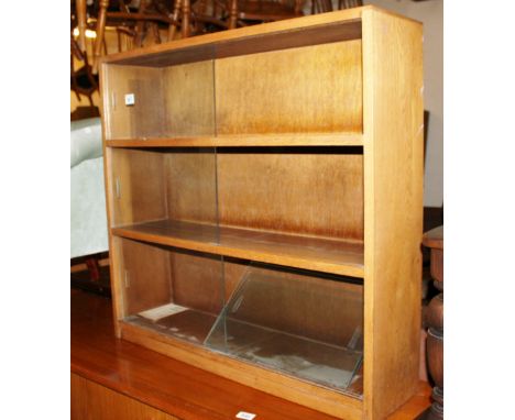 Light oak bookcase with three shelves and glazed sliding doors