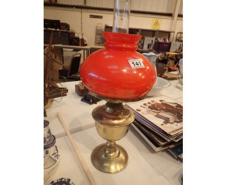 Brass oil lamp with red shade and chimney