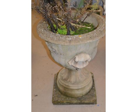 A large cast composition garden urn in two sections, standing on a square slab, 56cm diameter and 75cm high.