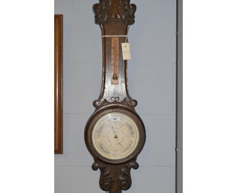 An aneroid compensated barometer in earlier carved and stained oak banjo patterned case with thermometer, 90cms.