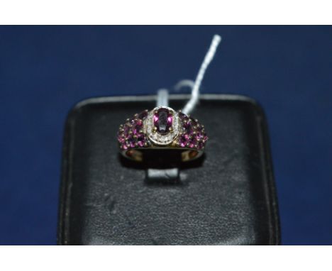 Garnet and diamond ring, the central garnet surrounded by a diamond bezel, flanked by garnet shoulders, on 9ct yellow gold sh