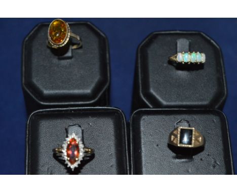 Four rings, set opal, onyx, amber and an orange stone.