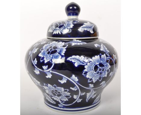 A vintage 20th Century India Jane blue &amp; white ceramic vase. Having a blue bulb top handle with lid, white floral and fol