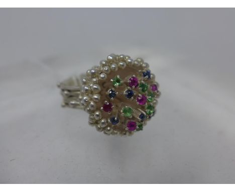 A sterling silver ring composed of a textural mount and shank set to the top with 5 rubies, 7 sapphires and 6 green garnets, 