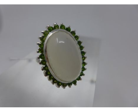 A sterling silver moonstone and green garnet cluster ring, the large central moonstone cabochon 2 x 1cm framed by an outer ro