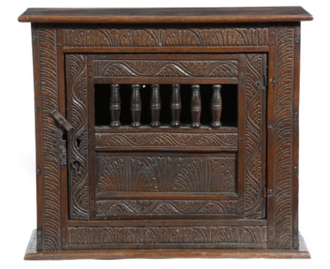 An early 18th century oak hanging food cupboard, the panelled front carved with lunettes and stylised leaves, with a pierced 