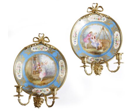 A pair of late 19th century French Sèvres style plate wall lights, each with a bleu céleste ground, with panels of flowers an