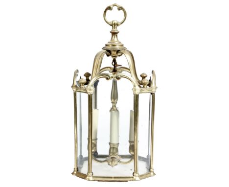 A Georgian style gilt brass hall lantern, with a 'C' scroll ring, above scroll supports and bud finials, with arched glass pa