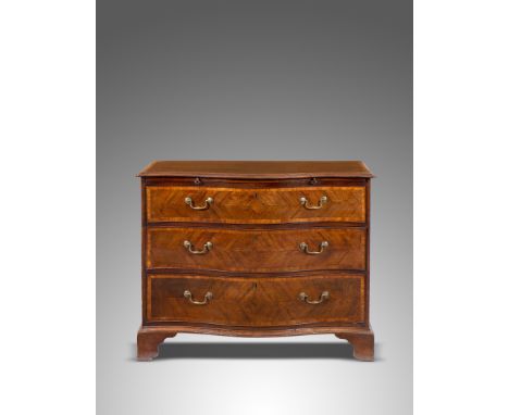 A George III mahogany serpentine commode, crossbanded in satinwood, the top with a moulded edge above a brushing slide and th