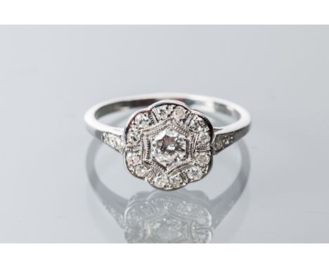 EARLY TWENTIETH CENTURY DIAMOND CLUSTER RING
the bezel of floral form, pierced and set with a central brilliant cut diamond o