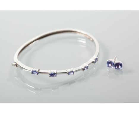 FOURTEEN CARAT WHITE GOLD TANZANITE BANGLE AND EARRING SET
the bangle set with five oval cut tanzanites; the stud earrings ea