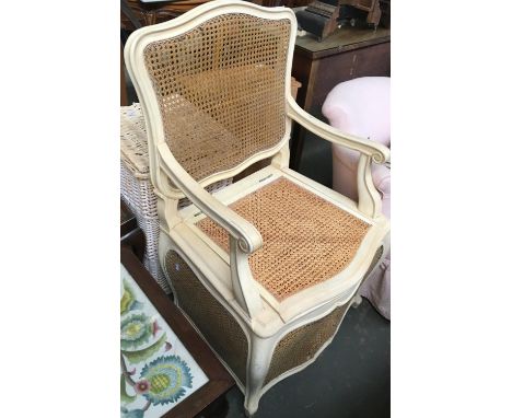 A caned commode chair, shaped back, scrolling arms, above shaped apron and cabriole legs, caned on three sides 