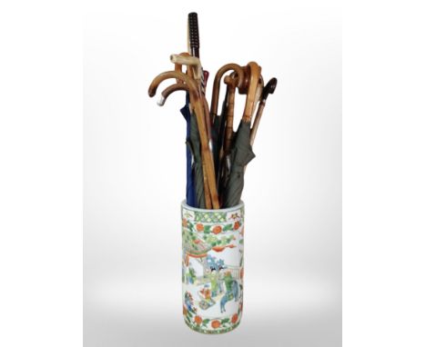 An oriental export porcelain cylindrical stick stand, height 43cm, containing various umbrellas.