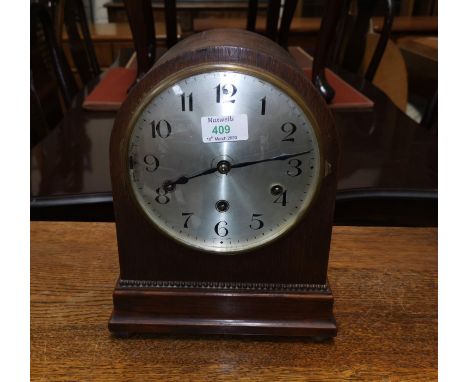 An oak cased mantel clock with arch top, reeded decoration and silvered dial 