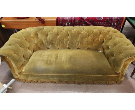 A three seater chesterfield settee with deep button back upholstered in gold length 190 cm on turned feet 