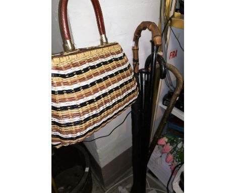 An ebony walking stick; 2 others; a cane handled umbrella; a 60's handbag 