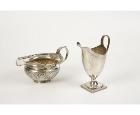 A GEORGE III CREAM JUG of helmet form with angular handle and bright-cut leaf engraved frieze, monogrammed, on a square base,