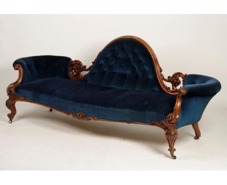 A VICTORIAN ROSEWOOD FRAMED SOFA, the arched raised back within a moulded and foliate carved surround, with button upholstere