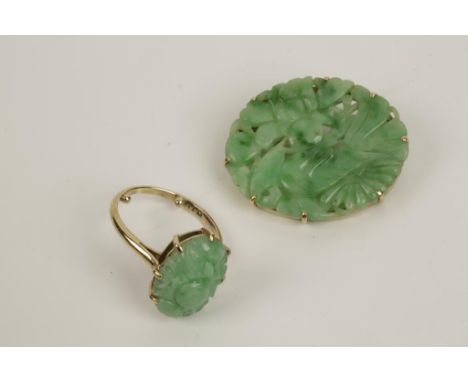 A CARVED JADE BROOCH, the oval green 'jade' panel carved with a bird and flowers, in unmarked yellow gold, c. 3.5cm wide and 