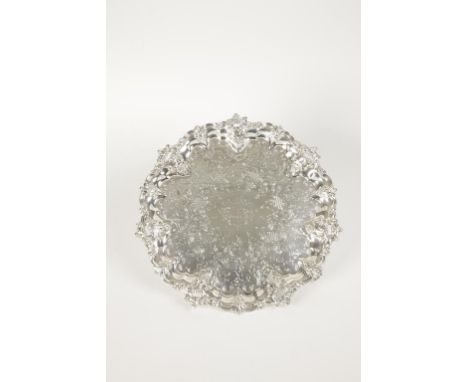 A VICTORIAN SALVER of shaped circular form with a raised and pierced leaf and scroll border, the centre chased with foliate s
