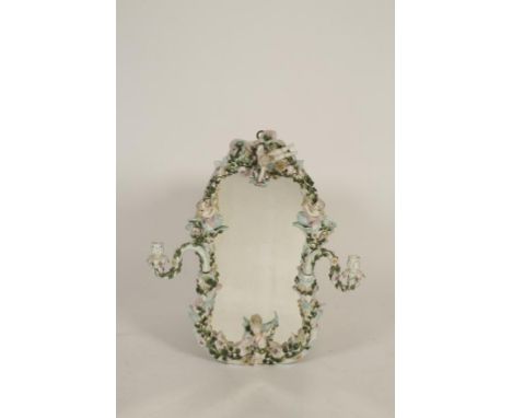 A DRESDEN STYLE FLORAL AND CHERUB ENCRUSTED WALL MIRROR, the shaped plate within a scrolling surround with twin candle branch