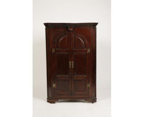 A GEORGE III MAHOGANY CORNER CUPBOARD, with arch moulded panelled doors with brass 'H' hinges, the moulded base with ogee bra