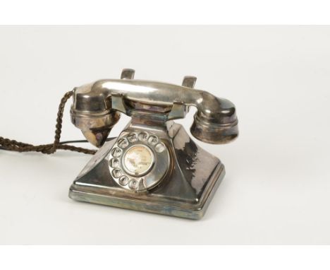 A VINTAGE SILVER PLATED TELEPHONE on a rectangular base with a circular dial, with wound cord flex, the receiver marked G.P.O
