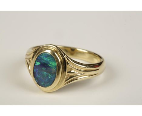 A BLACK OPAL RING, rub-over set to the centre with an oval black opal displaying strong dark blue and green tones, within a h