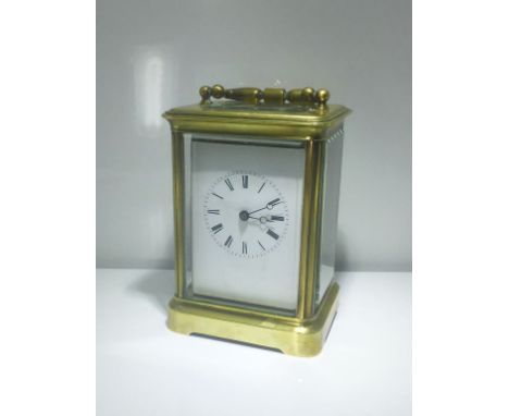 A FRENCH BRASS CASE STRIKING CARRIAGE CLOCK, the white enamel dial with Roman numerals, the movement striking on a bell, in a