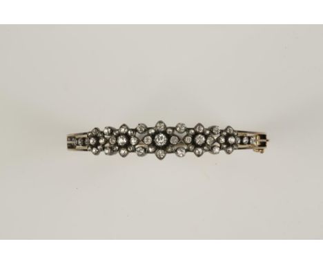 A VICTORIAN DIAMOND BANGLE,  the top section set with 5 old and rose-cut diamond graduated flowerhead clusters, with single d