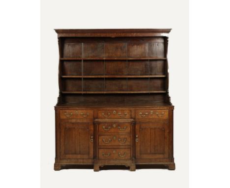 AN 18TH CENTURY OAK BREAK FRONT DRESSER, the simple moulded cornice above a serpentine shaped sides and three shelf Delft rac