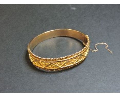 A 9ct gold repoussé hinged bangle, with milled wire decorative edge, Birmingham 1916