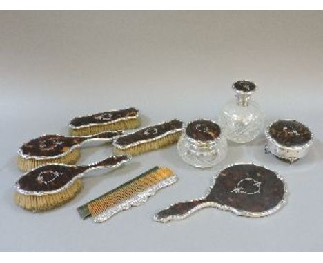 A tortoiseshell and silver dressing table set, comprising a pair of clothes brushes, a pair of hair brushes, a mirror, a silv