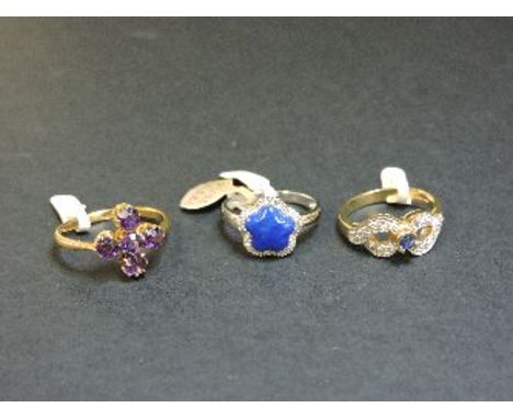 A 9ct gold sapphire and diamond ring, a 9ct white gold lapis lazuli and diamond cinquefoil cluster ring, and a purple paste c