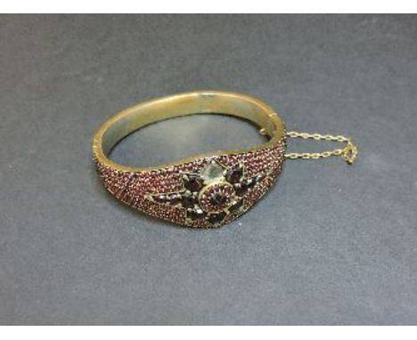 A Bohemian garnet gilt metal bangle, with a central star, some stones deficient