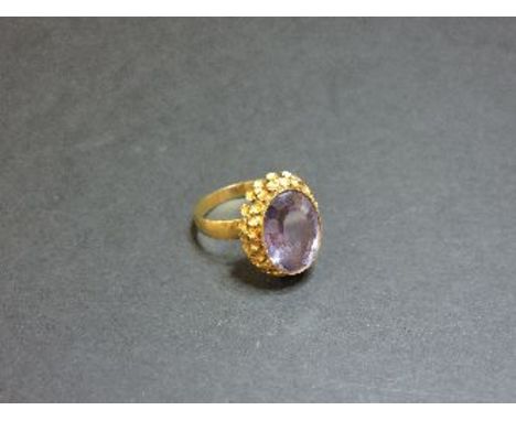 A Continental synthetic colour change sapphire gold ring, with a flower head border, tested as approximately 18ct gold