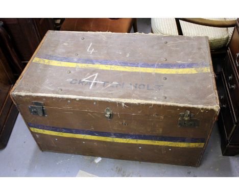 AN OLD BROWN TRAVELLING TRUNK of rectangular form containing a number of various textiles, a throw, a flat weave rug, fragmen