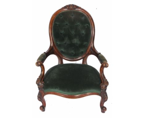 A VICTORIAN MAHOGANY FRAMED BUTTON UPHOLSTERED NURSING CHAIR with open arms and standing on carved scrolling legs