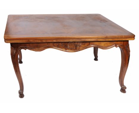 A FRENCH WALNUT DRAWER LEAF DINING TABLE, with parquetry inlaid top, standing on carved cabriole legs terminating in scrollin