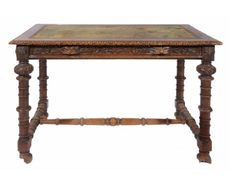 A VICTORIAN CARVED OAK WRITING TABLE complete with spare skiver, standing on ring turned legs, united by an H stretcher and l