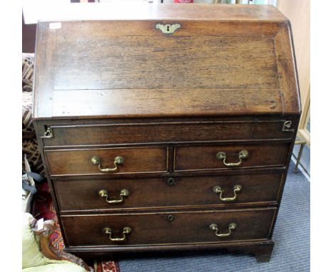 A GEORGE III OAK BUREAU the fall front enclosing a fitted interior of pigeon holes and drawers and central well, all over two