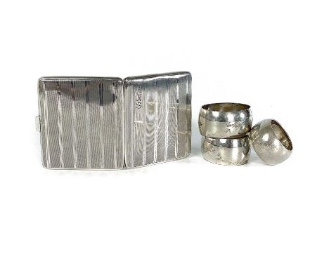A silver cigarette case and three silver napkin rings. The George V engine turned cigarette case hallmarked Birmingham 1926, 