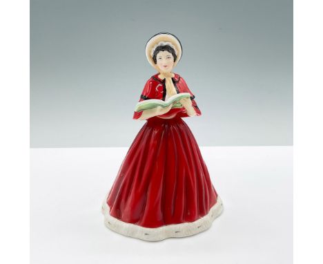 A black haired woman sings carols from a songbook, wearing a red flowing dress with white trim at the bottom and a black and 